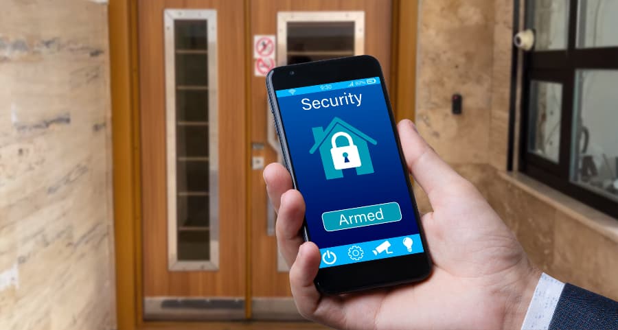 Individual using smartphone to arm a home security system